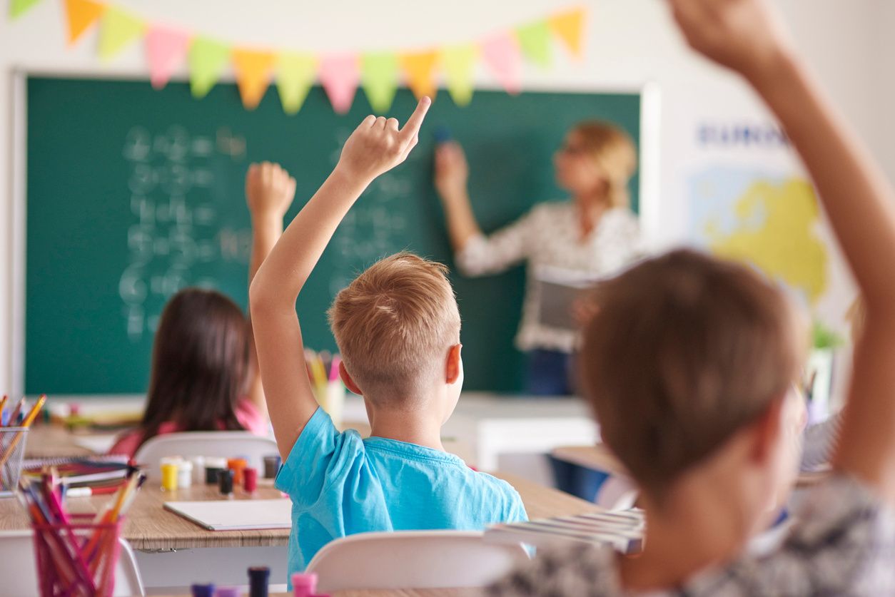 teacher-students-raising-hands-blurred